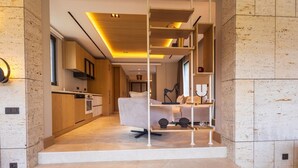 A modern interior with a kitchen, dining area, and staircase leading to a bedroom.