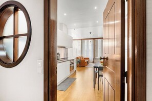 Eine moderne Küche mit weißen Schränken, ein Essbereich mit Tisch und Stühlen sowie eine große Holztür.