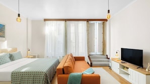 Ein modernes Hotelzimmer mit Bett, Sofa, Fernseher und einer Treppe zu einer oberen Etage.