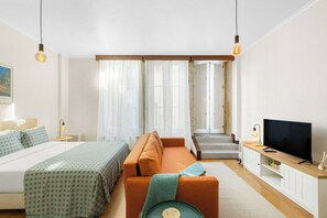 Ein modernes Hotelzimmer mit Bett, Sofa, Fernseher und einer Treppe zu einer oberen Etage.