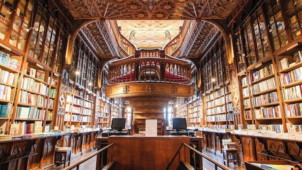 Ein Bibliotheksinneres mit aufwendig gestalteten Holzbögen, einem zentralen Lesebereich und einem detailreichen Deckenornament.