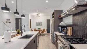 A modern kitchen with a central island, built-in appliances, and a dining area with a view. - Villa 2 at Troon North, Luxury Golf Villa with Shuffleboard + Poker (Scottsdale)