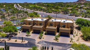 A residential area with multiple two-story buildings, a curved road, and sparse vegetation. - Villa 2 at Troon North, Luxury Golf Villa with Shuffleboard + Poker (Scottsdale)