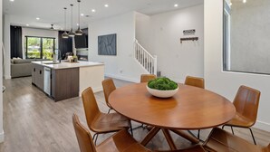 A modern kitchen with a central island, dining area with a round table and chairs, and a staircase leading to an upper level. - Villa 2 at Troon North, Luxury Golf Villa with Shuffleboard + Poker (Scottsdale)