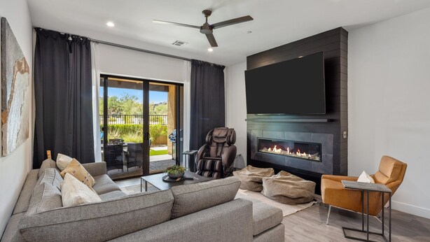 A modern living room with a grey sofa, a massage chair, a flat-screen TV, and a fireplace. - Villa 2 at Troon North, Luxury Golf Villa with Shuffleboard + Poker (Scottsdale)