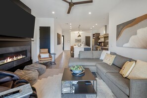 Ein modernes Wohnzimmer mit Kamin, einer Couch, einem Couchtisch und einem Fernseher.