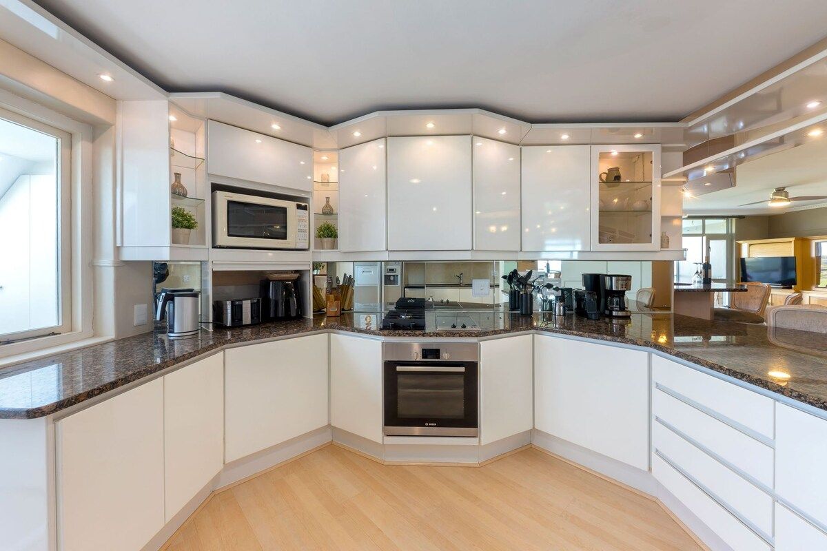 A modern kitchen with white cabinetry, a built-in oven, and a granite countertop.
