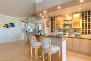 Cozinha com área de bar, cadeiras de madeira e uma vitrine de vidro.