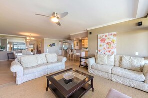 A spacious living area with two sofas, a coffee table, and a ceiling fan.