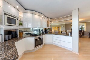 Una cocina moderna con armarios blancos, encimeras de granito y electrodomésticos de acero inoxidable.