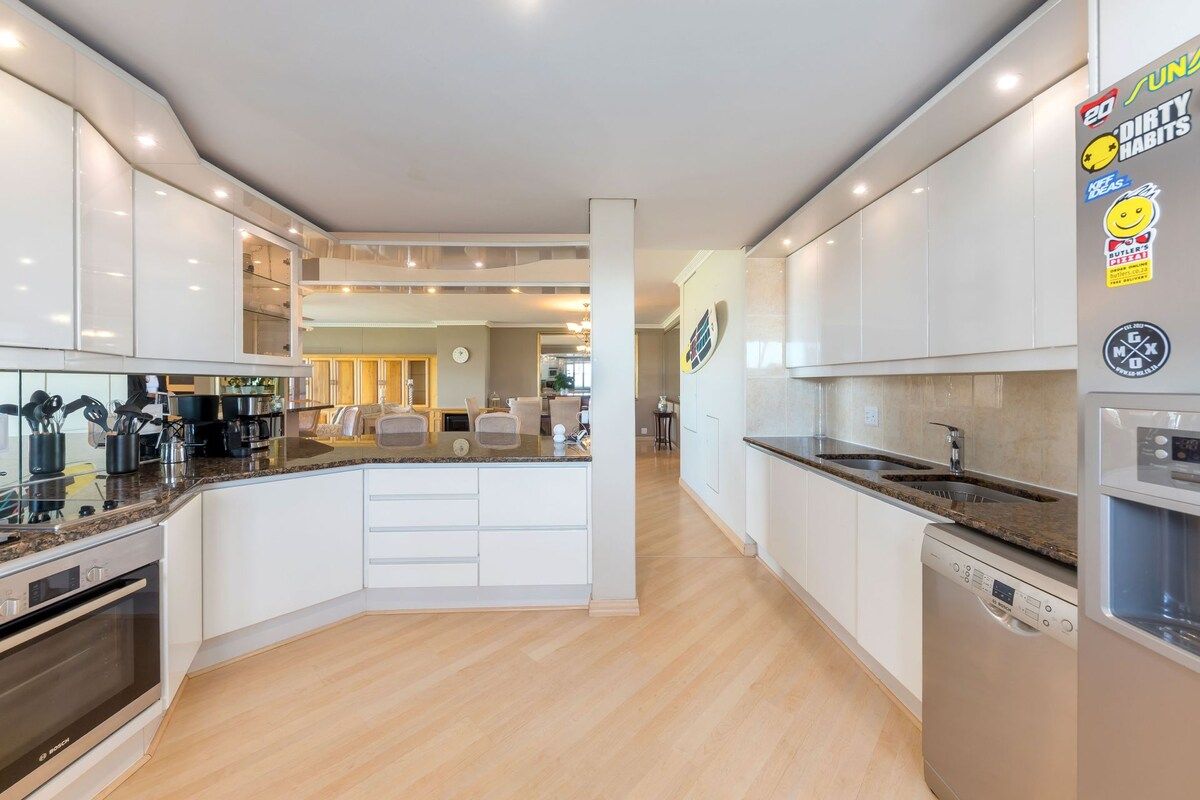 A modern kitchen with white cabinets, a central island, and built-in appliances.