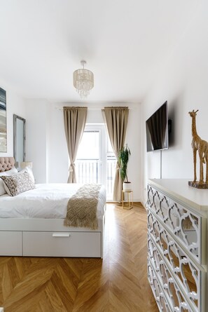 Ein Schlafzimmer mit Bett, Fernseher, einer Giraffe als Dekoration, einer Pflanze und einer Chandelier.