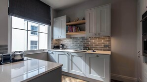 A modern kitchen with white cabinets, a herringbone-patterned backsplash, and a large window. - Central, Secure Parking and High-end (Nottingham)