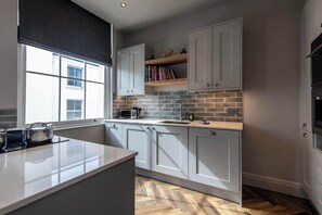 A modern kitchen with white cabinets, a herringbone-patterned backsplash, and a large window. - Central, Secure Parking and High-end (Nottingham)