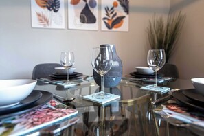 A dining table with a vase, two wine glasses, and a bowl. - Central, Secure Parking and High-end (Nottingham)