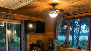 Une chambre dans un chalet en bois, équipée d’un lit, d’une télévision, d’un bureau et offrant une vue sur l’extérieur.