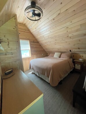 A bedroom with a bed, bedside tables, a ceiling fan, and a window. - Adorable Lakeside Cabin w/ Private Sandy Beach to Enjoy the Sunrise (Menahga)