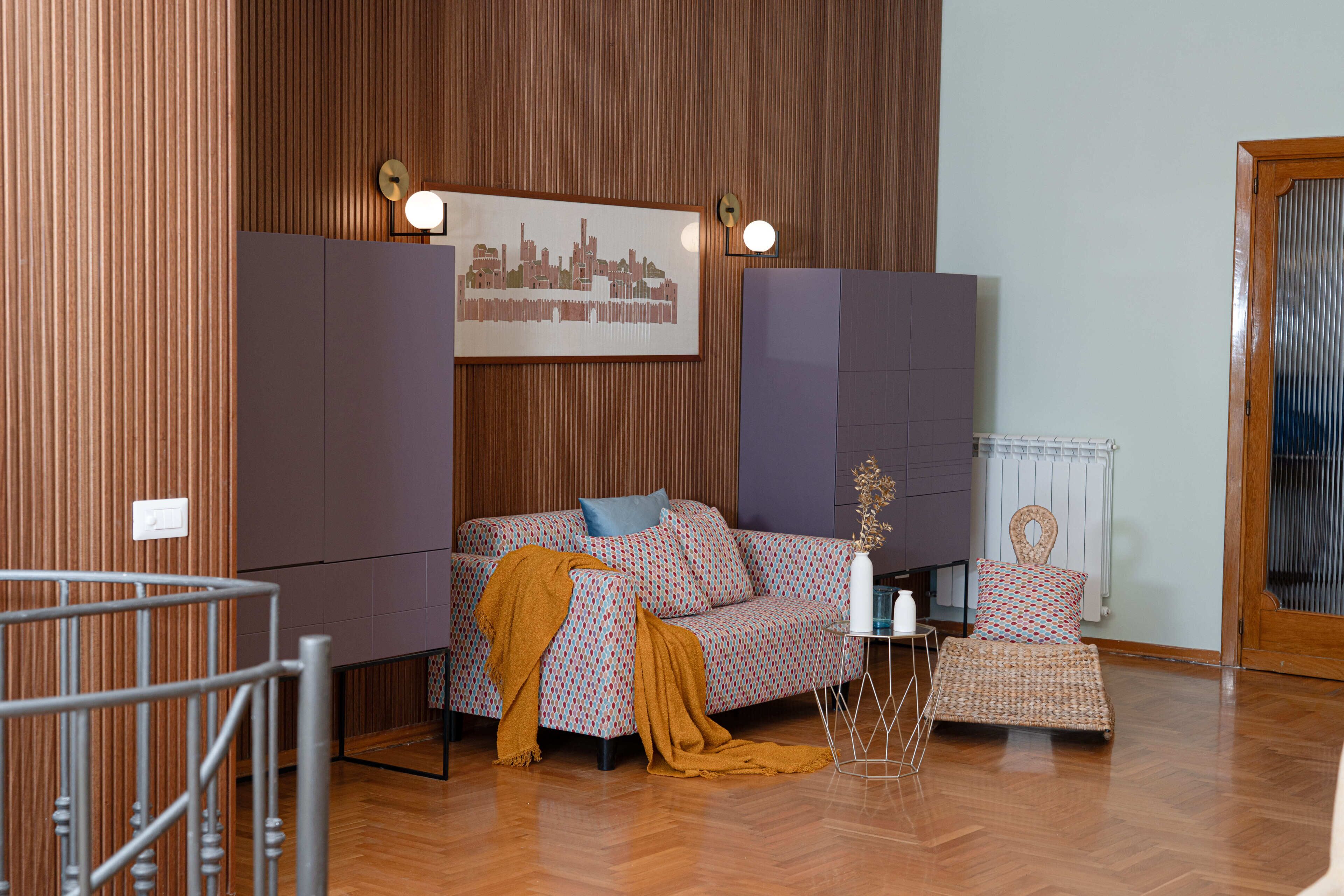 Ein Zimmer mit einer Couch, einem kleinen Tisch, einem Sessel, einer dekorativen Vase und einem gerahmten Bild an der Wand.