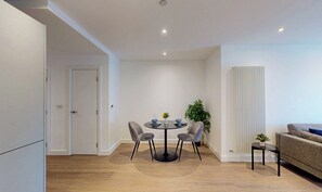 Ein moderner Essbereich mit einem runden Tisch, vier Stühlen und einer Vase mit Blumen.