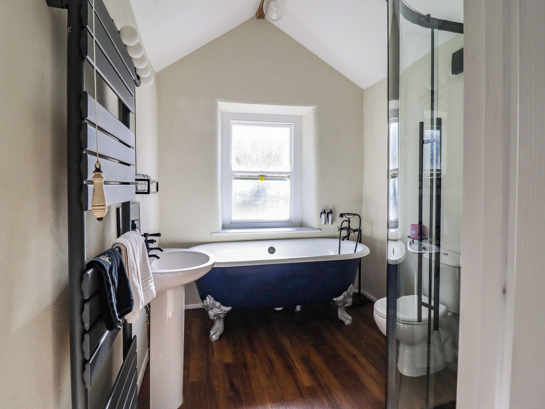 A bathroom with a freestanding bathtub, a sink, and a window.