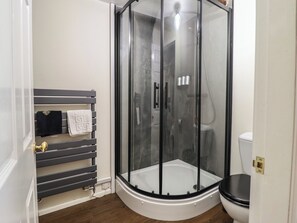 A bathroom with a glass-enclosed shower, a toilet, and a towel rack with towels. - Plas Dolguog (Machynlleth)