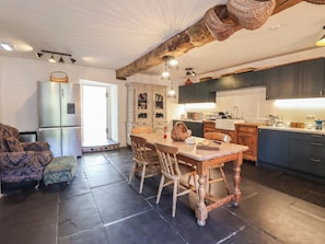 A kitchen with dark cabinets, a wooden dining table, and a refrigerator.