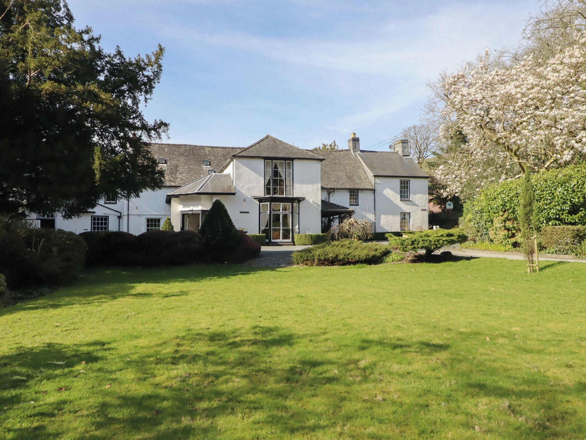 A large white building with a symmetrical facade, a central entrance, and a well-maintained lawn.