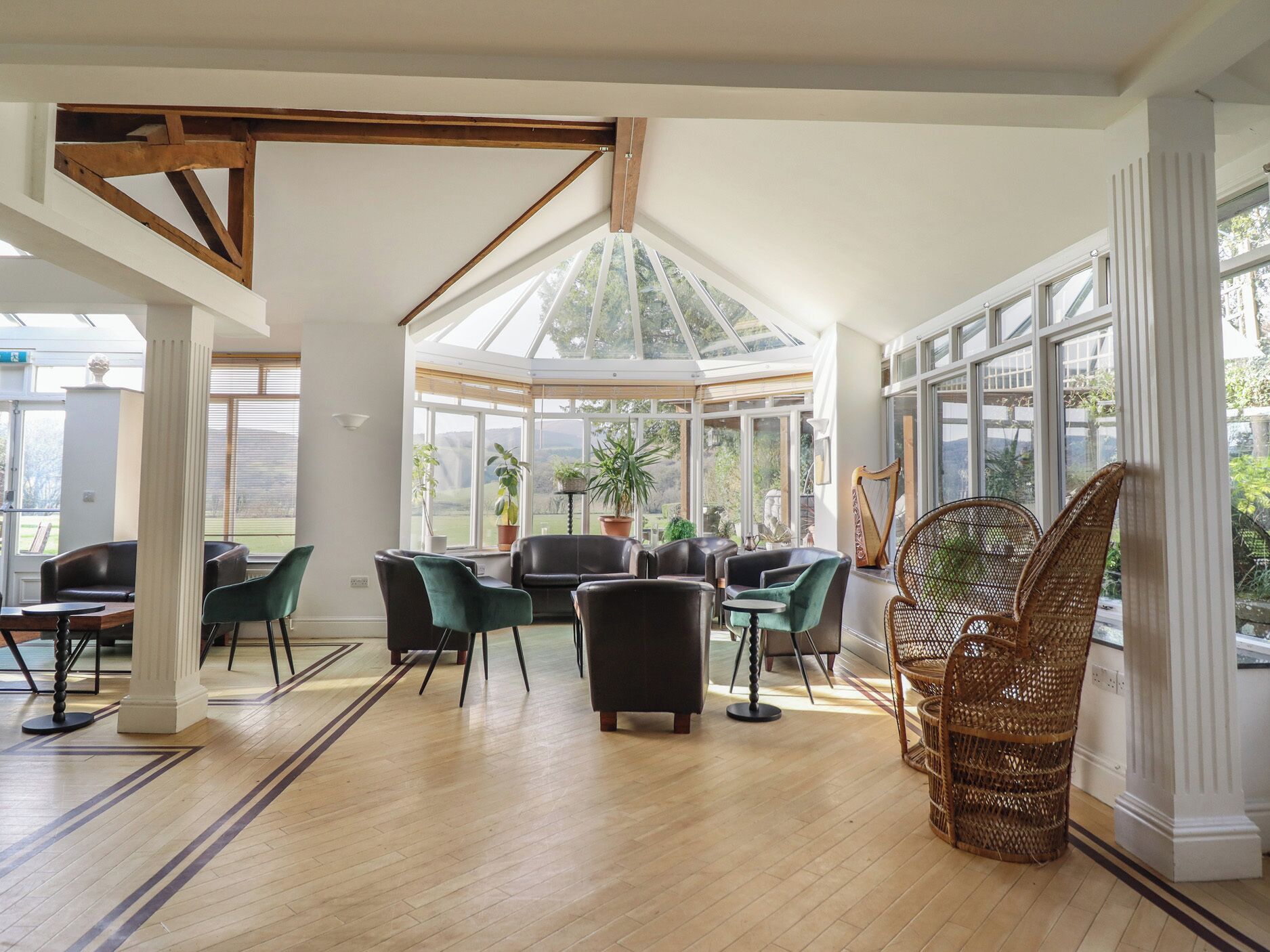A conservatory with a high ceiling, wooden beams, and large windows.