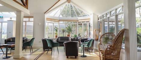 A conservatory with a high ceiling, wooden beams, and large windows.