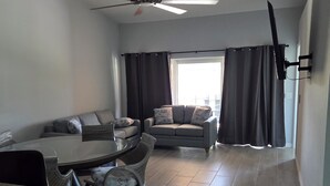 A living room with a ceiling fan, a dining table with chairs, a sofa, and a window with curtains. - 1 floor 3bedroom 2full bathroom  apartment in Bokeelia with AC 2vehicle garage (Bokeelia)