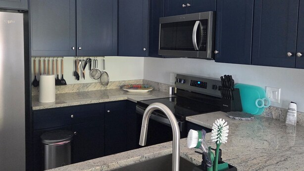 A modern kitchen with dark cabinets, a stainless steel sink, a microwave, and a granite countertop. - 1 floor 3bedroom 2full bathroom  apartment in Bokeelia with AC 2vehicle garage (Bokeelia)