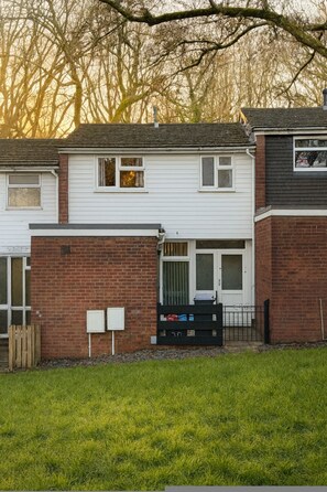 A two-story residential building with a brick facade, a white upper floor, and a visible front door. - Comfortable Two-bedroom Home in St Dials Cwmbran (Cwmbran)