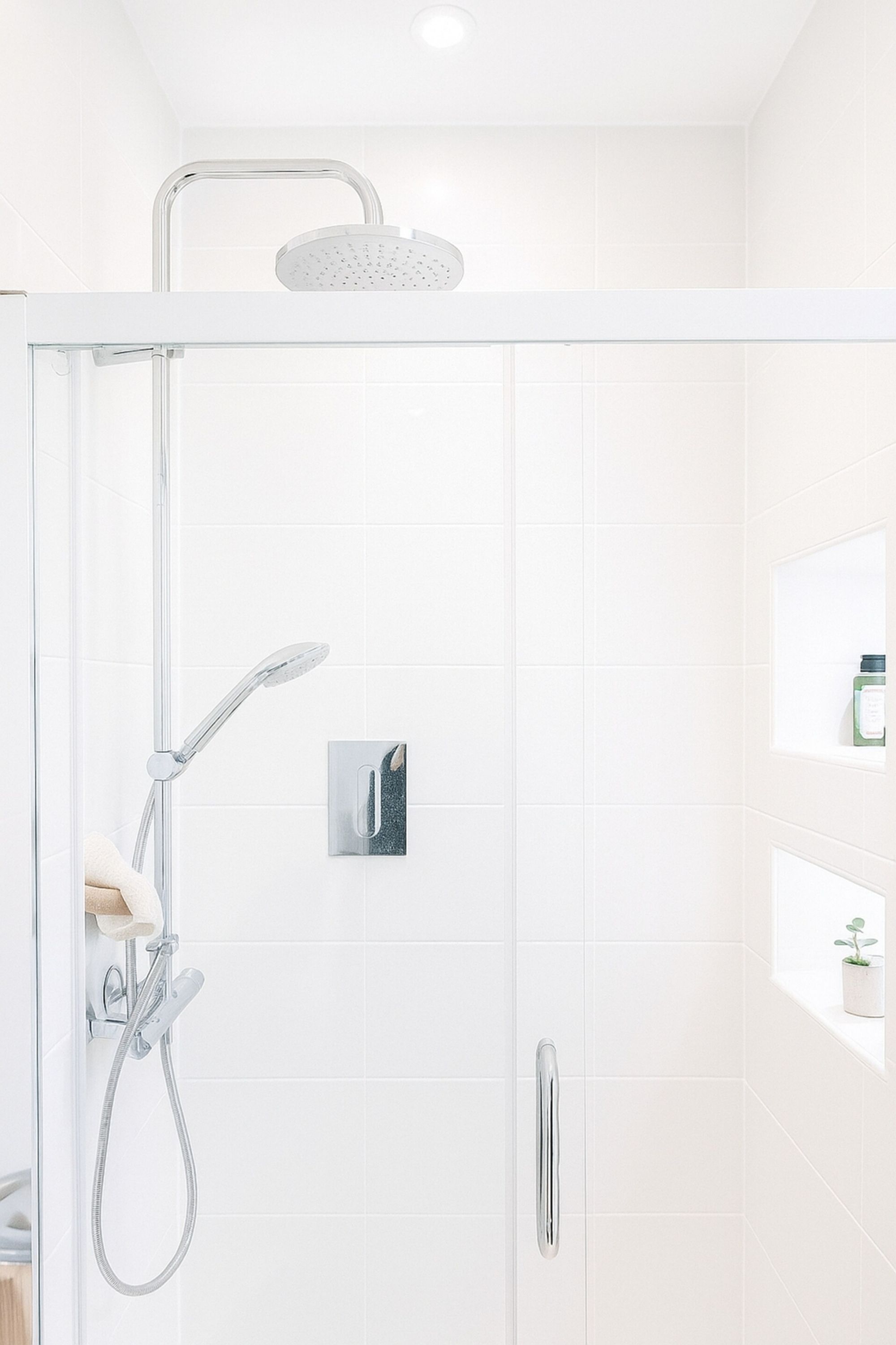 Eine moderne Duschkabine mit Handbrause und einer an der Wand montierten Bedienpanel.