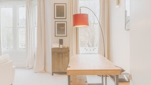 Een kamer met een houten tafel, een bankje, een kast en een vloerlamp.