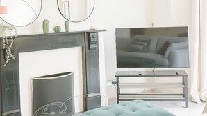 Een moderne woonkamer met een open haard, televisie en comfortabele zithoek.