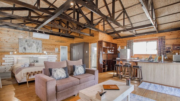 L’intérieur chaleureux d’un chalet avec un plafond en bois, un canapé, une table à manger et un coin cuisine.