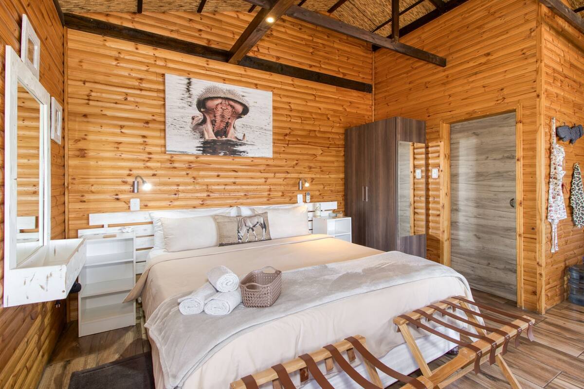 Une chambre à coucher de style cabane en bois, avec un lit, des tables de chevet, une armoire et un tableau au mur.