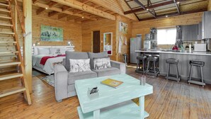 L’intérieur d’un chalet en bois comprend un canapé, une table basse, un coin cuisine et un escalier.