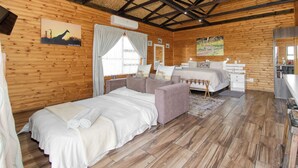 Une pièce de cabane en bois comprenant un lit, un canapé et une petite kitchenette.