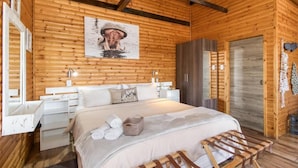 A wooden cabin-style room with a bed, a wardrobe, and a mirror.