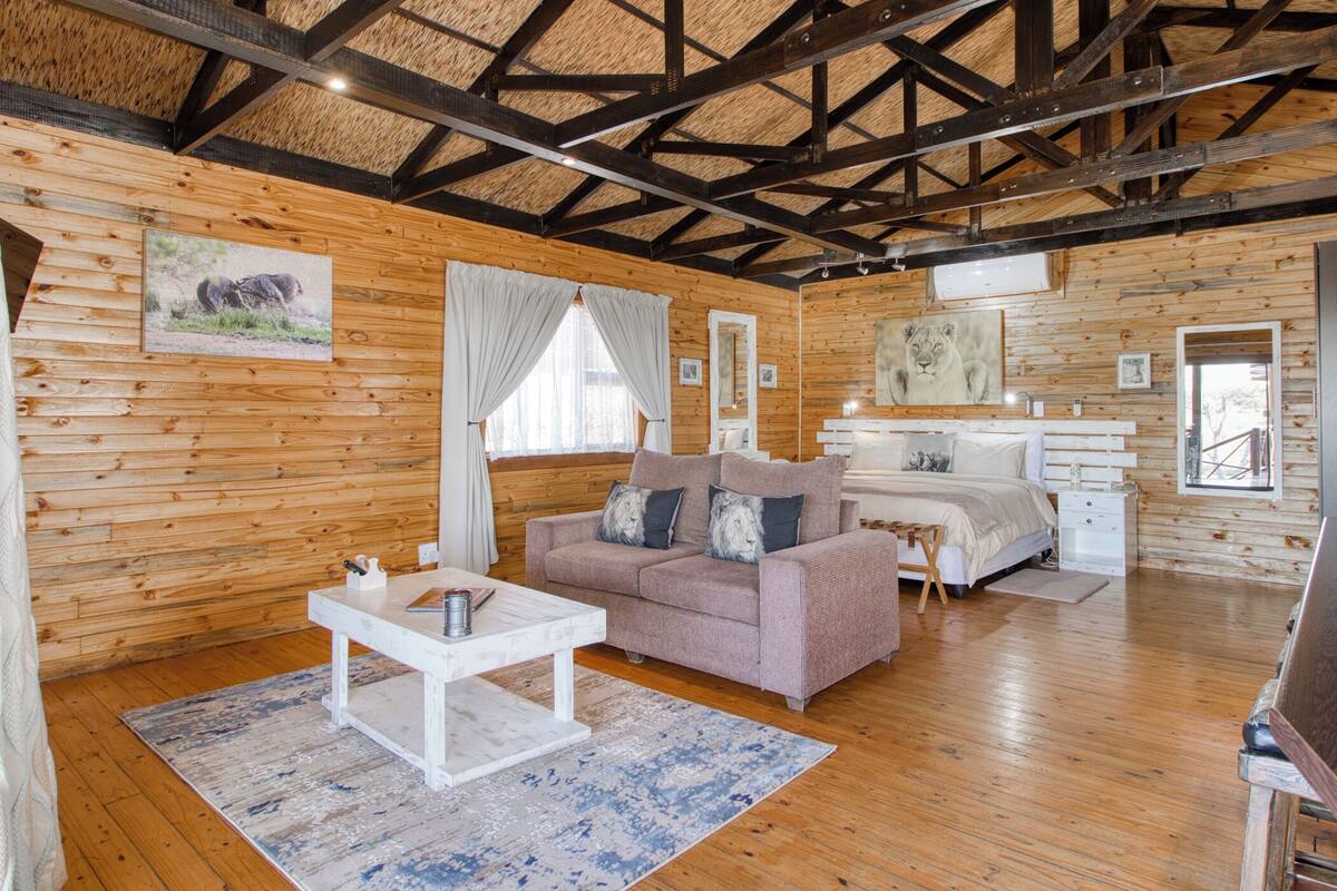 Un intérieur en bois comprenant un lit, un canapé, une petite table et un miroir.