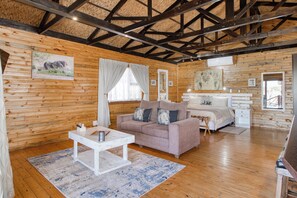 A wooden interior with a bed, a sofa, a small table, and a mirror.