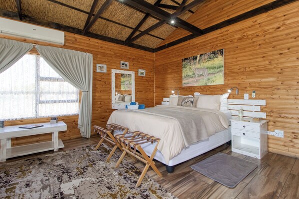 A wooden-paneled room with a bed, bedside tables, a desk, and a bench.