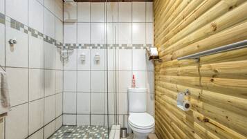 A small, tiled shower area with a wooden wall and a toilet.