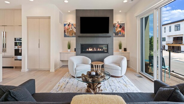 Una sala de estar moderna con chimenea, dos sillones, un sofá y una mesa de centro de vidrio.
