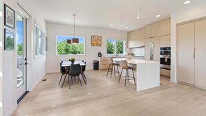 Una cocina moderna con una isla central, armarios de madera y ventanas amplias.