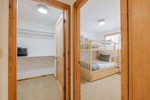 A room with bunk beds, a closet, and a door leading to another room.