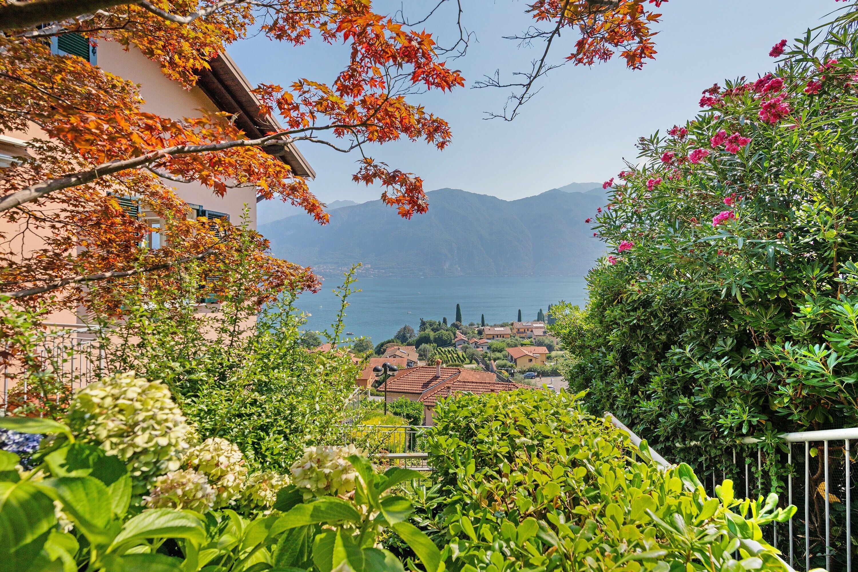Ein Wohngebiet mit Häusern, einem Garten und Blick auf das Meer und die Berge.