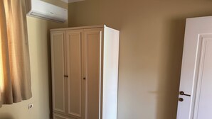 Une pièce avec une armoire, une porte et une couvre-lit à motifs.