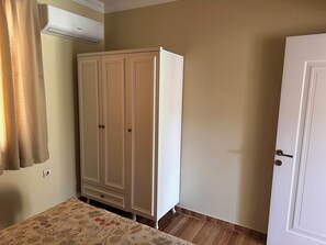 Une pièce avec une armoire, une porte et une couvre-lit à motifs.
